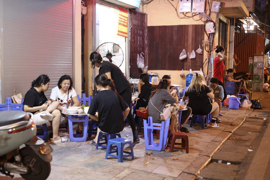 People eating on low plastic stools at a Vietnamese street-food stall