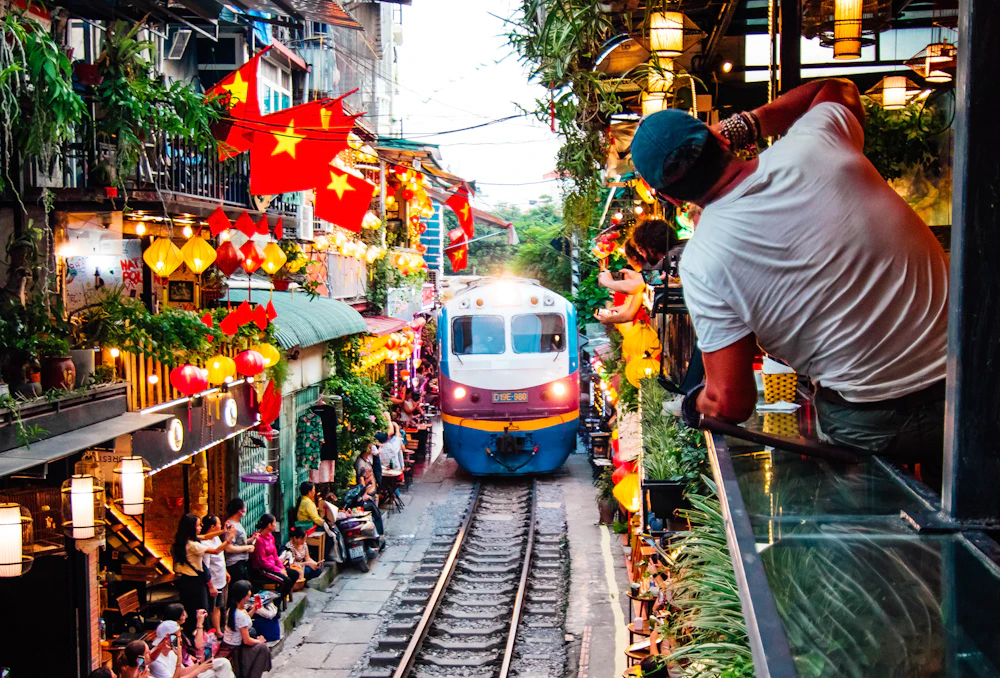 A train passing through Hanoi's Train Street between cafés and lanterns